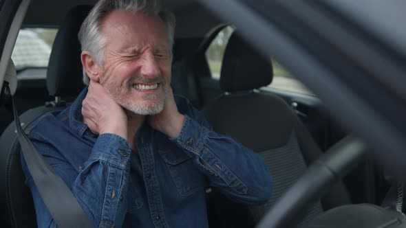 Senior male driver with whiplash injury sitting in car after traffic accident alt