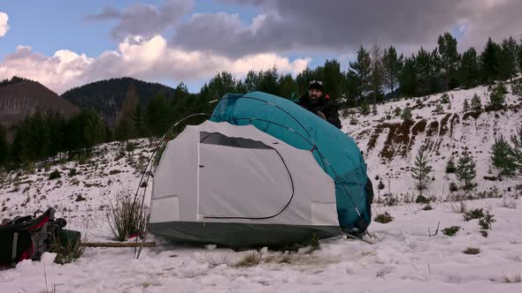 Hiker pitching tent in winter in the mountains. alt