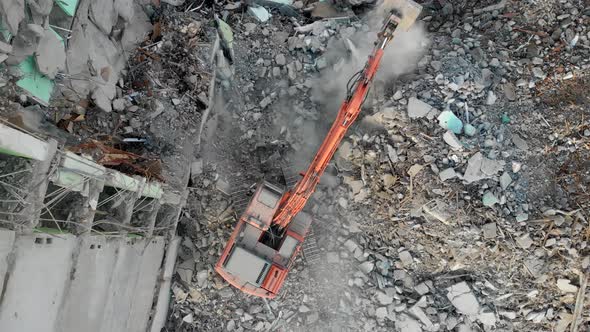 An Excavator Tractor Digs the Concrete Ruins of a Collapsed House with a Bucket