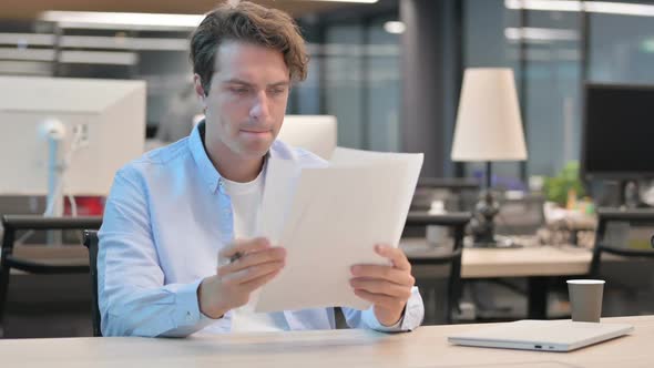 Man Reading Documents While Sitting in Office alt