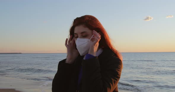 Girl with Red Hair Takes Off Her Mask and Breathes Clean Air Near the Ocean alt