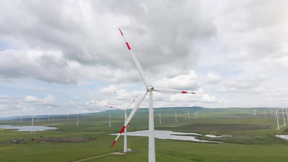 Wind Farm with Spinning Windmill Generator Located on the Windy Landscape alt