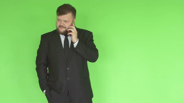 Caucasian Man in a Black Business Suit with a Beard Solves Problems By Phone on the Background alt