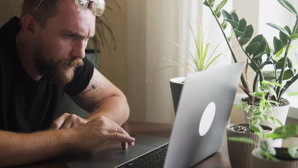 Bearded Man Using Computer for Remote Work at Home