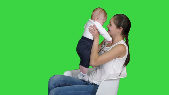 Mother and Cute Baby Sitting on a Chair on a Green Screen, Chroma Key alt
