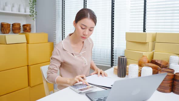 Asian beautiful woman check vase goods order for customer from shelf. alt