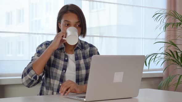 A Young AfricanAmerican Woman Looks at the Laptop Screen and Communicates