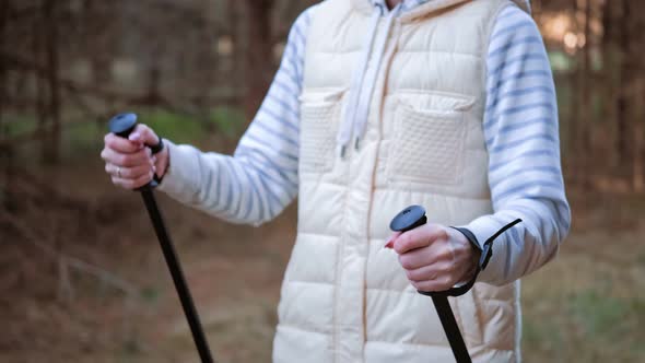Close Up Hands of Active Female Holding Trekking Poles Going at Spring Forest alt