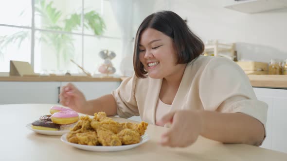 Asian plus size fat girl feeling hungry and ready to eat fried chicken and sweet donut on table. alt