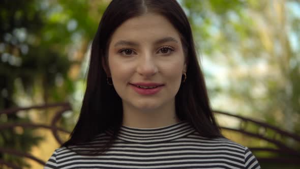 Young Woman Talking to Camera Video Chat Sitting on Bench in Park