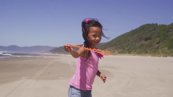 Young girl playing with bubbles at beach