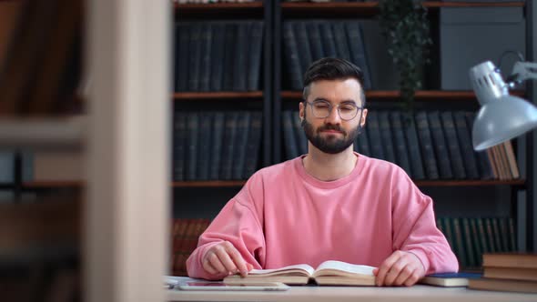 Successful Clever Man Posing at Public Library Desk with Open Paper Book Smiling Enjoying Break alt