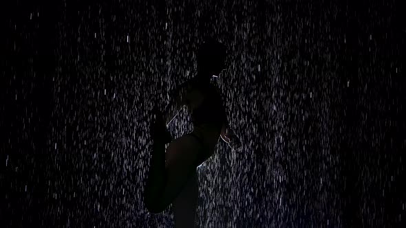 Dancer Pose in the Pouring Rain. Wet Body Silhouette of Young Woman Practicing Yoga Exercises in alt
