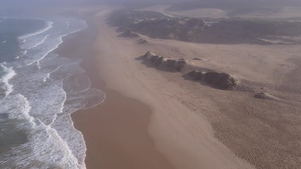 Drone Flying Along Coast with Waves Seen Flowing Into Shoreline