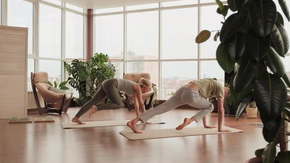 Couple At Yoga Class Doing Legs Stretching alt