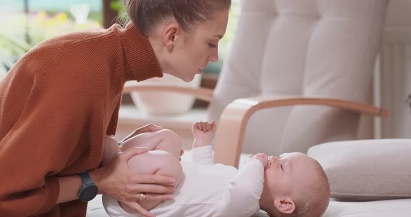 Close Up of the Baby Lying on Its Back on the Couch Smiling and Happy Looking at Its Mother Who alt