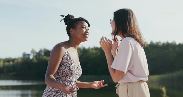 Two Friends of Different Nationalities Meet at the Lake Outside After a Long Time Tell a Story alt