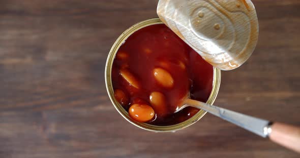 Tin Jar with Beans in Tomato Sauce on the Table. On a Wooden Background.  alt