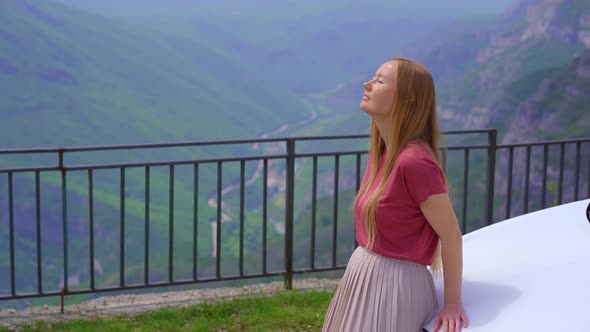 A Young Woman is Relaxing Standing By a Car at a Viewpoint on a Beautiful Canyon of the Cijevna alt