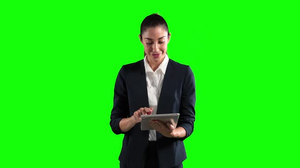 a Caucasian woman in suit using a tablet in a green background