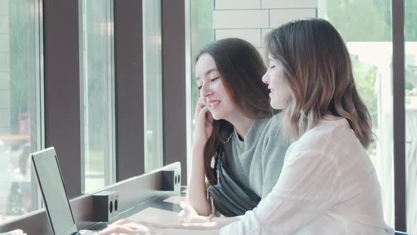Two Young Women Studying Together at Campus Cafe Using Laptop alt