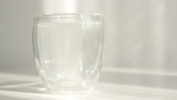 Glass with effervescent carbon tablet close-up 4K footage alt