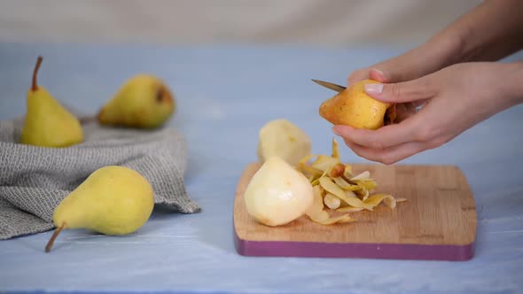 Woman Peeling Pear for Dessert Over Table