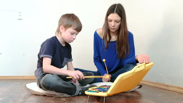 Mom and Son Playing Xylophone Sitting in a Room on the Floor.