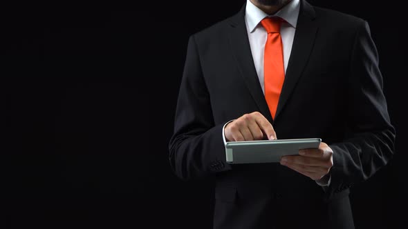 Man in Black Suit Working with a Tablet in His Hand Presses His Finger in Front of Himself Then alt