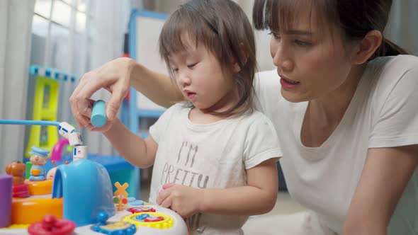 Asian happy family, beautiful mother and little girl kid playing toy together in living room at home alt