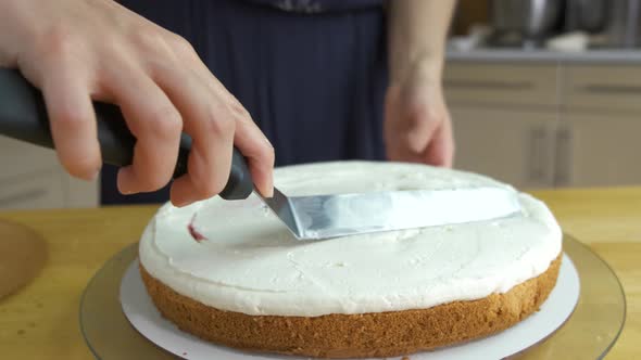 Close up of woman hands making sweet cake with white cream and biscuit. alt