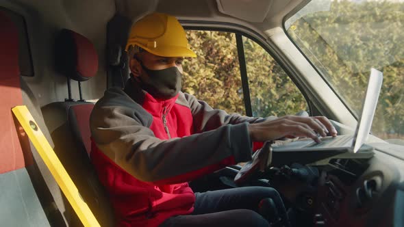 Man with Helmet and Face Mask Using Tablet and Leveler Tool in the Van alt