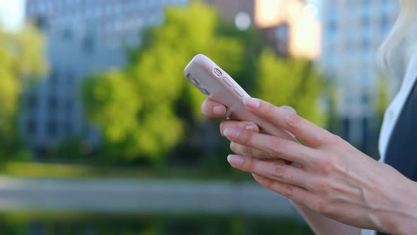 close-up woman uses a smartphone on the background of the city