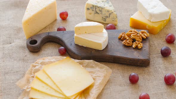 Cheese Platter with Nuts and Grapes on a Wooden Cutting Board alt