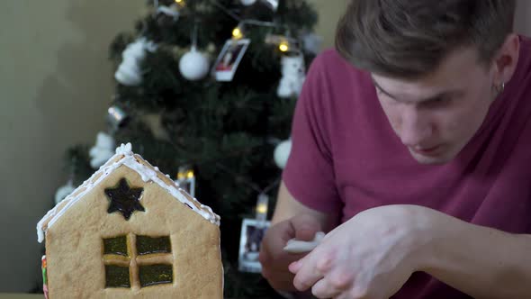 A Guy Decorates a Christmas Gingerbread House alt