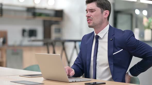 Hardworking Businessman with Laptop Having Back Pain in Office alt