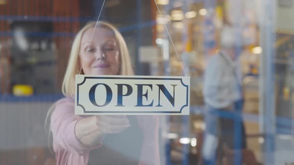 Happy Mature Female Owner Turn Closedopen Sign on Coffee Shop Glass Door alt