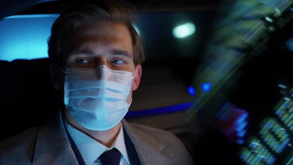Young Businessman in Medical Mask Sitting in a Moving Car and Using Laptop Man Top Manager in a Suit alt