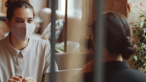 Young Woman in Face Mask Talking with Female Friend in Cafe alt
