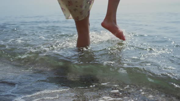 Young Woman Falling Down in Ocean Water Holding Hat alt