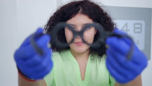 Smiling Charming Young Ophthalmologist Stretching Trial Glasses Imitating Putting on Patient alt