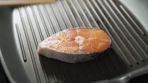 The Man's Hand Puts a Piece of Salmon on a Hot Frying Pan alt