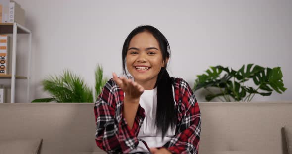 Girl waving hand while sitting on couch alt