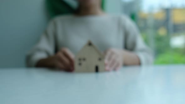 Closeup of a woman holding and showing wooden house model