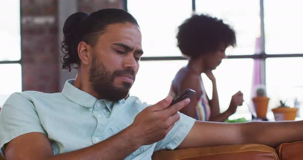 Happy mixed race man sitting in cafe talking on smartphone and smiling alt