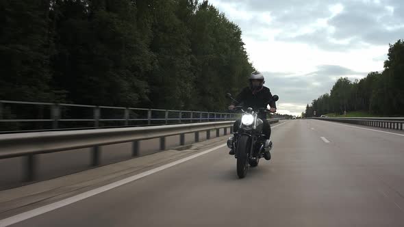Man Riding Scrambler Motorbike on the Highway Through the Forest Front View alt