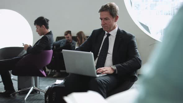 Business man waiting in airport lounge working on laptop