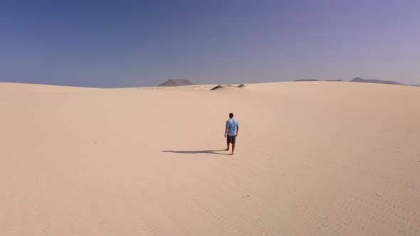 Young Man Walks Along the Sand in the Rays of the Scorching Sun, Fuerteventura