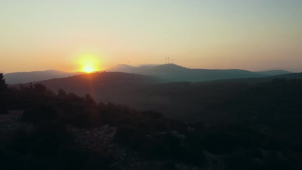 Wind generators at the top of the hill stand motionless in calm weather alt