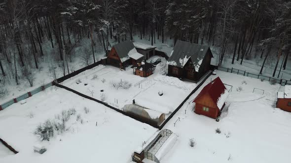 Aerial Fly Over the Houses in the Winter Forest on a Frosty Cloudy Day